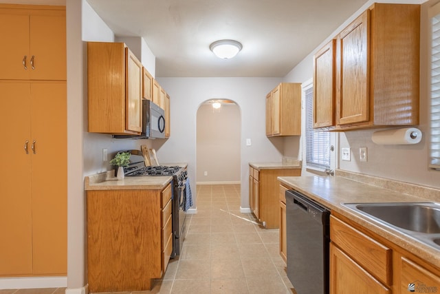 kitchen featuring sink, stainless steel range, light tile patterned flooring, and black dishwasher