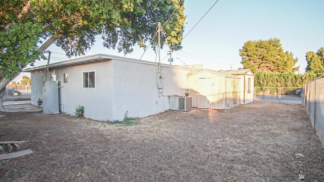 rear view of house featuring central AC and a storage shed