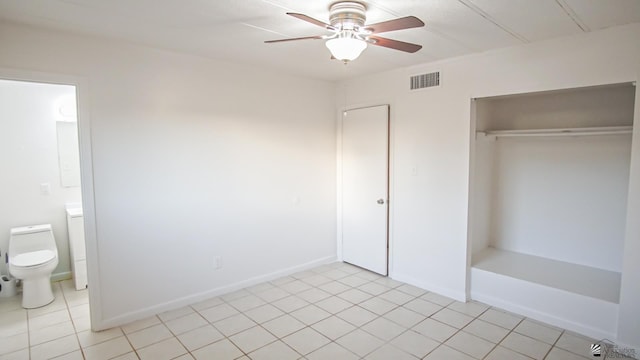 unfurnished bedroom featuring light tile patterned floors, a closet, ceiling fan, and ensuite bathroom