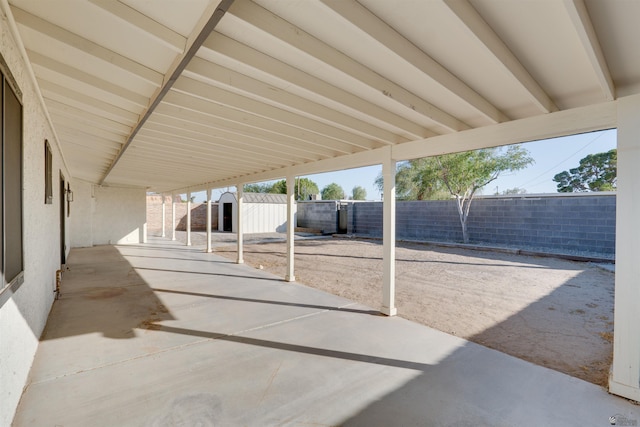 view of patio with an outbuilding, a storage unit, and a fenced backyard