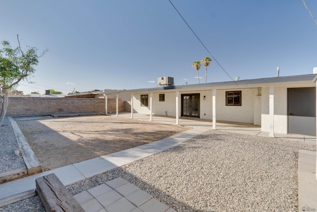 rear view of property with a patio area, fence, central AC unit, and stucco siding