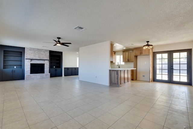 unfurnished living room featuring built in shelves, french doors, visible vents, a ceiling fan, and a textured ceiling