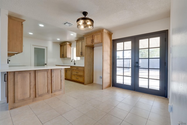 kitchen with french doors, a wealth of natural light, light countertops, visible vents, and a peninsula