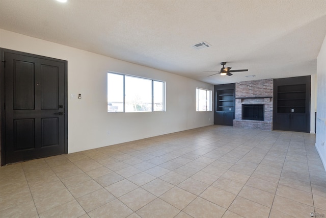 unfurnished living room with visible vents, built in features, a textured ceiling, a fireplace, and light tile patterned flooring