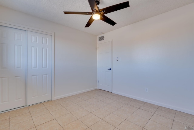 unfurnished bedroom with light tile patterned floors, baseboards, visible vents, a textured ceiling, and a closet