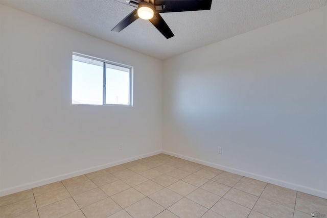 empty room featuring a ceiling fan, a textured ceiling, baseboards, and light tile patterned floors