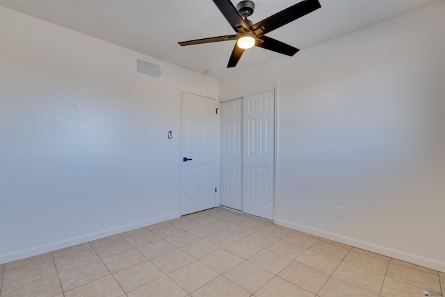 unfurnished room featuring ceiling fan, light tile patterned floors, a textured ceiling, visible vents, and baseboards