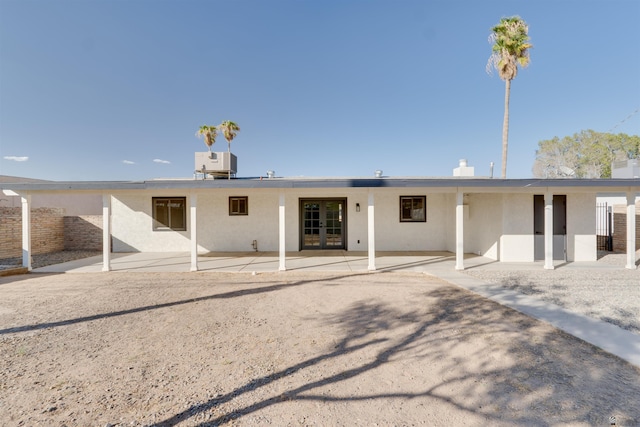 back of property with a patio area, central AC unit, stucco siding, and french doors