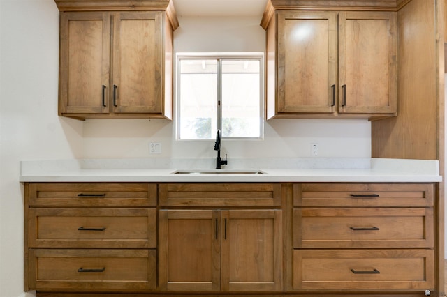 kitchen featuring light countertops, a sink, and brown cabinets