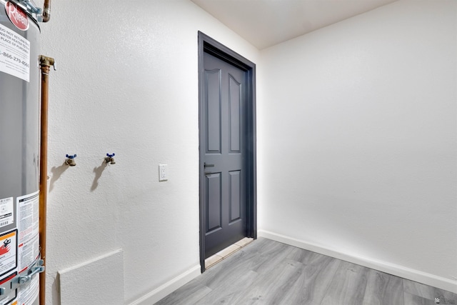 interior space featuring gas water heater, light wood-style flooring, and baseboards