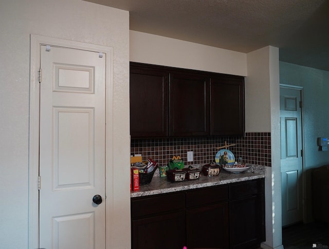 kitchen with dark brown cabinets, tasteful backsplash, and light countertops