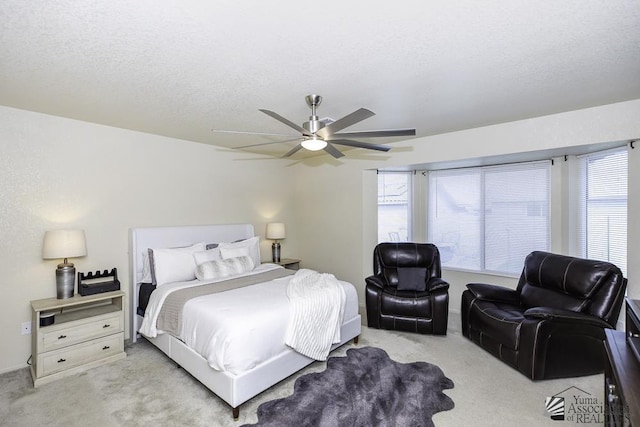 carpeted bedroom featuring ceiling fan, multiple windows, and a textured ceiling