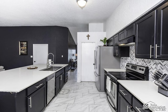 kitchen featuring sink, backsplash, stainless steel appliances, a center island with sink, and a textured ceiling