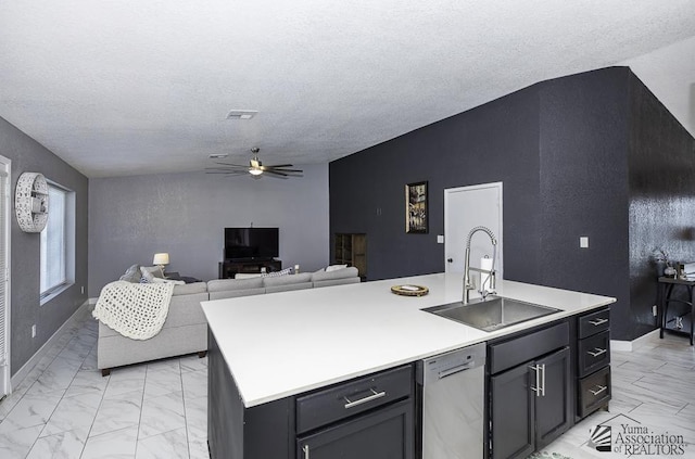 kitchen with sink, a textured ceiling, stainless steel dishwasher, ceiling fan, and a kitchen island with sink