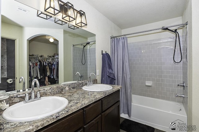 bathroom featuring vanity, shower / bathtub combination with curtain, and a textured ceiling