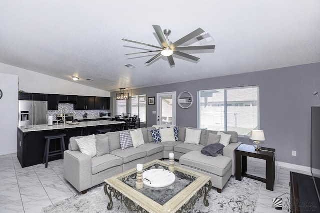 living room with lofted ceiling, sink, and ceiling fan with notable chandelier