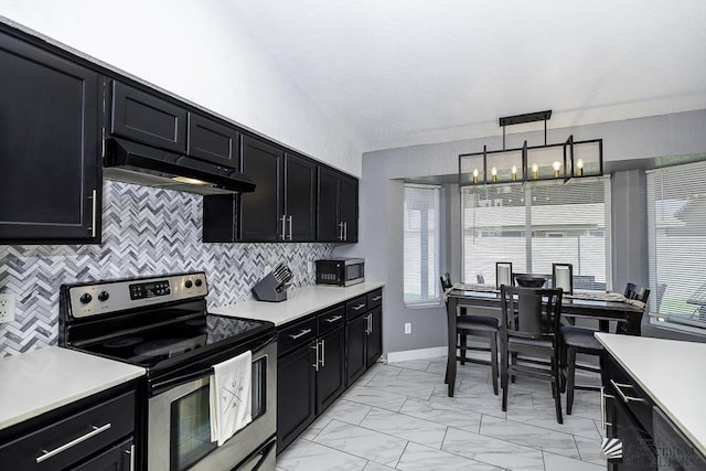 kitchen featuring appliances with stainless steel finishes, pendant lighting, range hood, backsplash, and an inviting chandelier