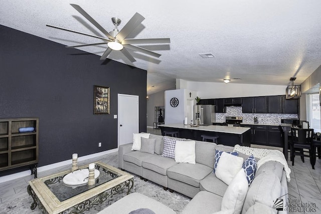 living room featuring vaulted ceiling, ceiling fan, and a textured ceiling