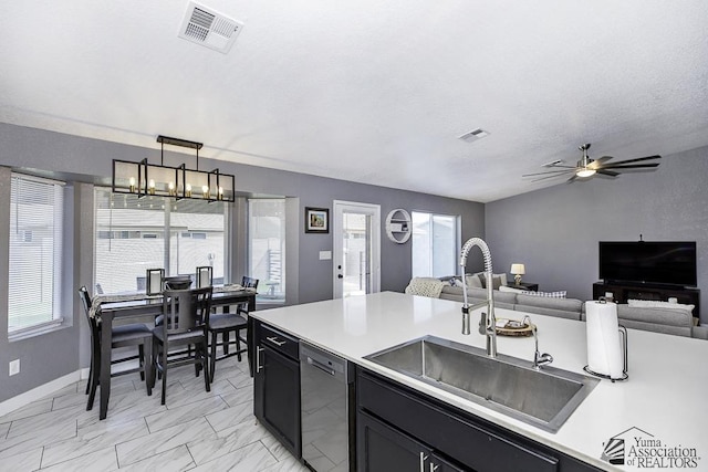 kitchen with sink, a textured ceiling, stainless steel dishwasher, pendant lighting, and ceiling fan with notable chandelier