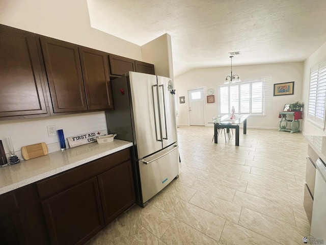 kitchen featuring lofted ceiling, light countertops, high quality fridge, and dark brown cabinetry