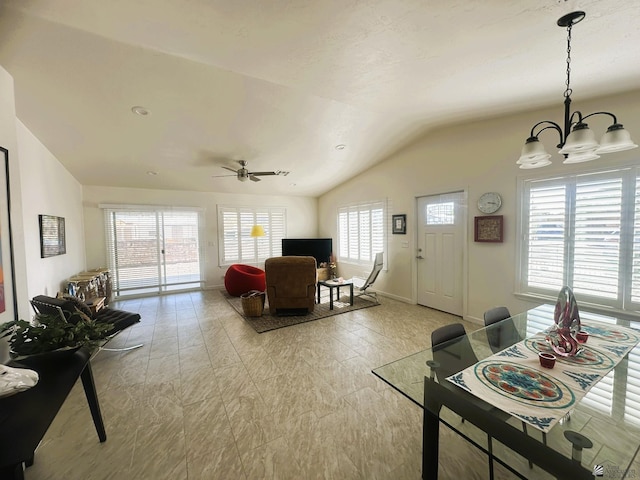 living room featuring lofted ceiling, baseboards, and ceiling fan with notable chandelier