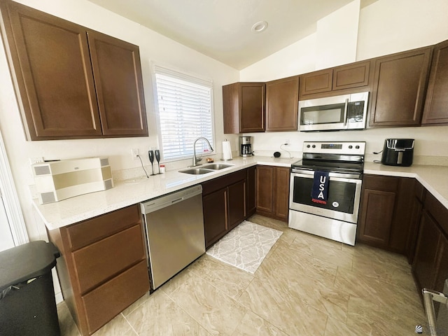 kitchen featuring lofted ceiling, dark brown cabinetry, a sink, light countertops, and appliances with stainless steel finishes