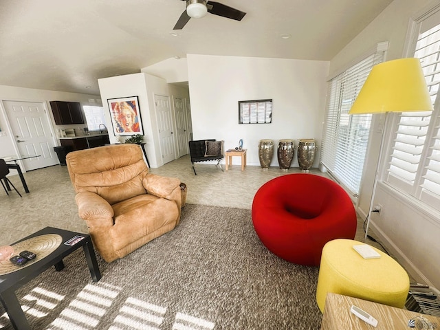 living area featuring carpet flooring, vaulted ceiling, baseboards, and ceiling fan