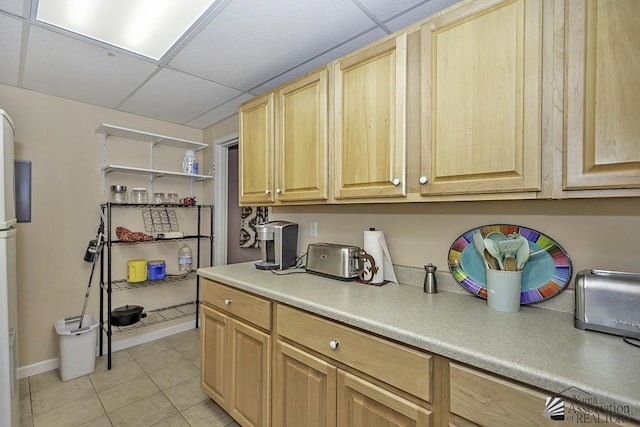 kitchen featuring light tile patterned flooring, a paneled ceiling, and light brown cabinetry