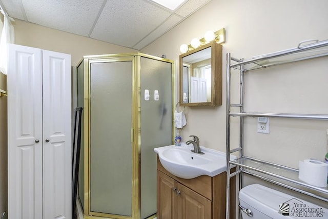 bathroom featuring a paneled ceiling, vanity, toilet, and an enclosed shower