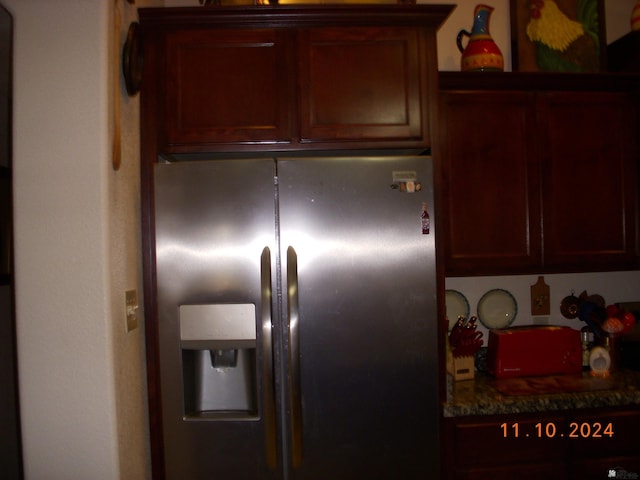 kitchen featuring dark stone countertops and stainless steel refrigerator with ice dispenser