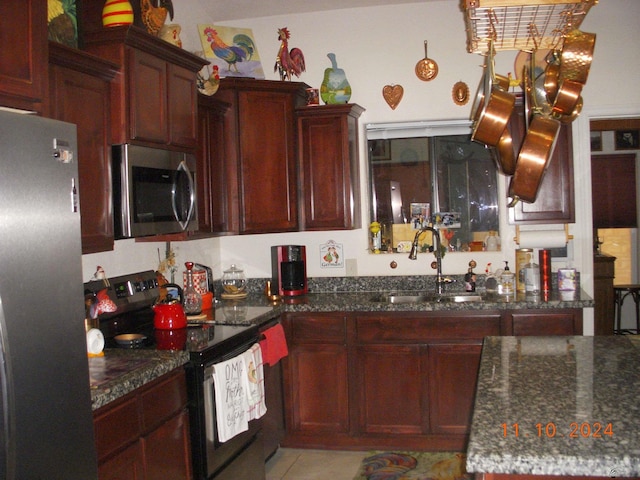 kitchen featuring light tile patterned floors, sink, appliances with stainless steel finishes, and dark stone counters