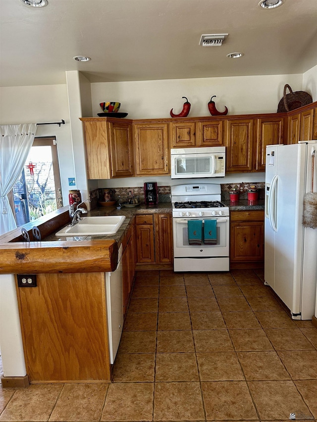 kitchen featuring dark tile patterned floors, sink, kitchen peninsula, and white appliances