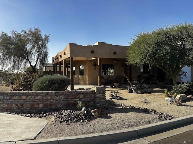 pueblo revival-style home featuring ceiling fan and a patio