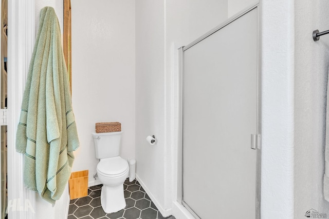 bathroom featuring a shower with shower door and toilet