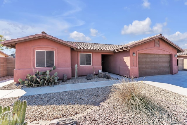 ranch-style house with a garage, driveway, a tile roof, and stucco siding