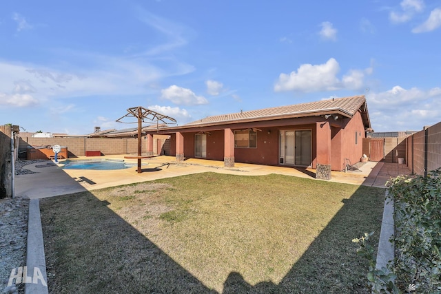 back of property with a fenced backyard, a tiled roof, a lawn, a fenced in pool, and a patio area