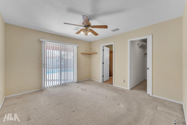 interior space featuring baseboards, visible vents, light colored carpet, ceiling fan, and a textured ceiling