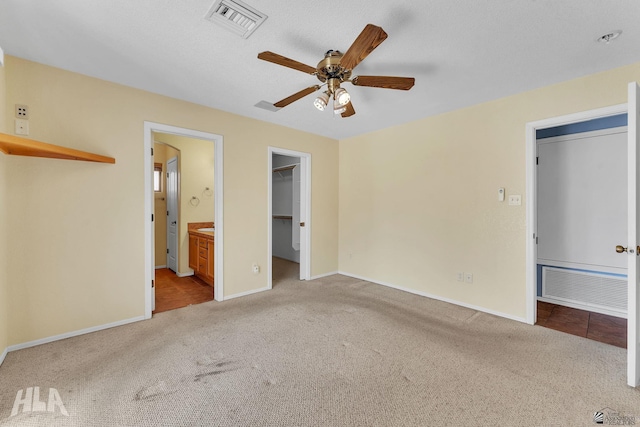 unfurnished bedroom with a walk in closet, light colored carpet, visible vents, and baseboards