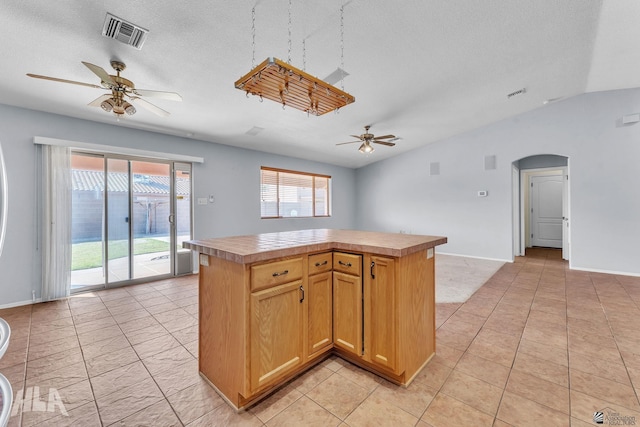 kitchen with a center island, arched walkways, visible vents, a ceiling fan, and a textured ceiling