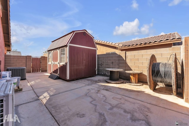 view of patio featuring central air condition unit, a fenced backyard, a storage unit, and an outdoor structure