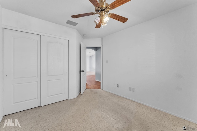 unfurnished bedroom featuring a closet, light colored carpet, ceiling fan, and baseboards