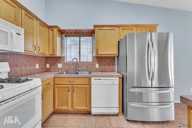 kitchen with light tile patterned floors, white appliances, a sink, backsplash, and tile counters