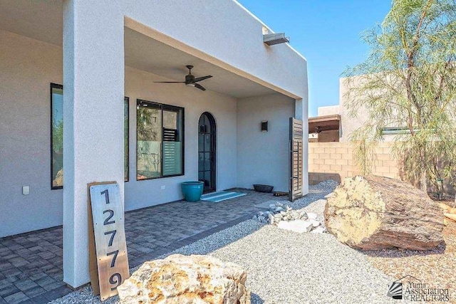 entrance to property with ceiling fan and a patio area