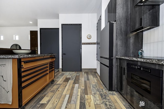 kitchen featuring stainless steel fridge, wall oven, and dark hardwood / wood-style floors