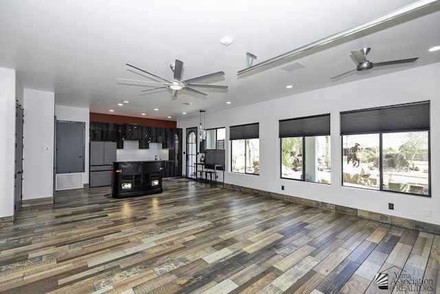 unfurnished living room with dark wood-type flooring, ceiling fan, and plenty of natural light