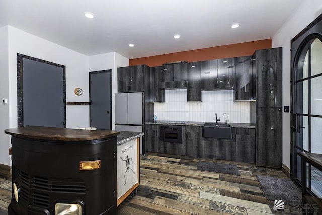 kitchen featuring black electric stovetop, decorative backsplash, dark hardwood / wood-style floors, oven, and sink