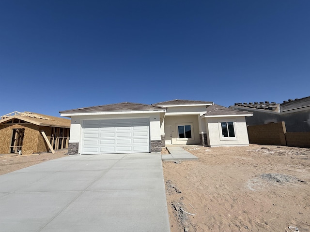 view of front of house with a garage, driveway, stone siding, and stucco siding