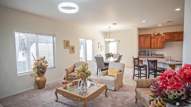 carpeted living room featuring a notable chandelier and sink