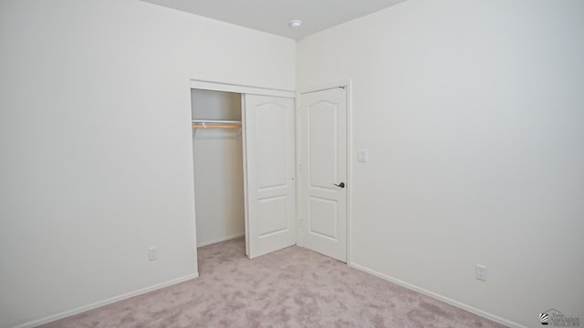 unfurnished bedroom with light carpet and a closet