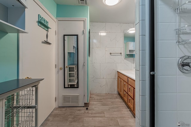 bathroom featuring hardwood / wood-style floors, vanity, and tile walls